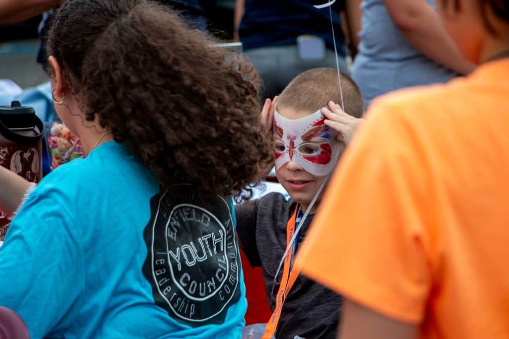 A young gentlemen gets his face painted by one of the many members of the Enfield Youth Council.
