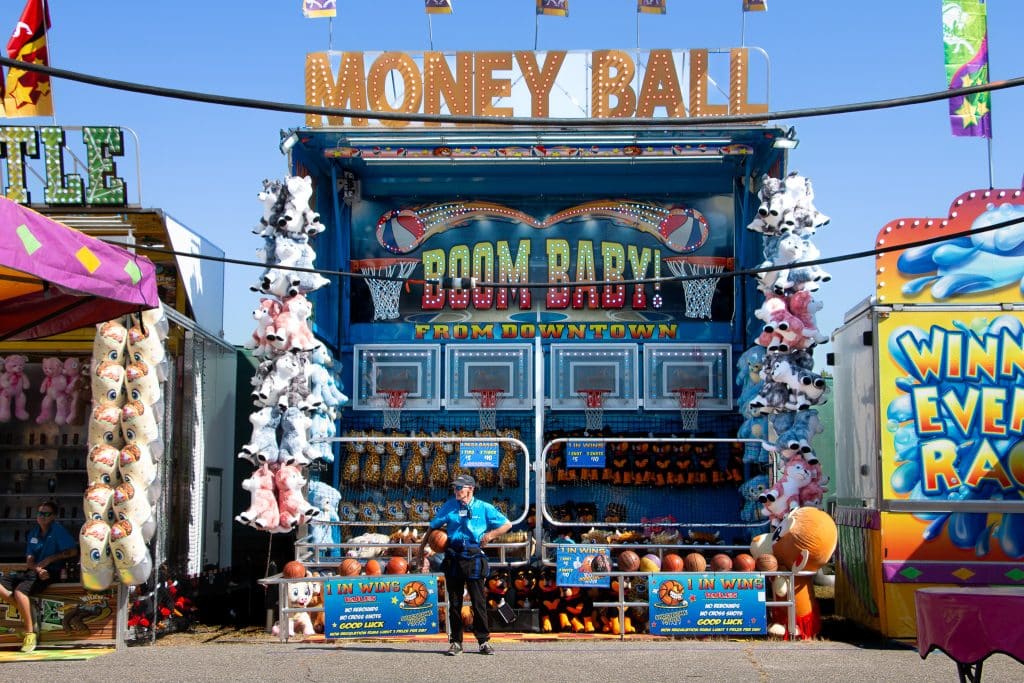 A man standing in front of a basketball carnival game at the Big E fair